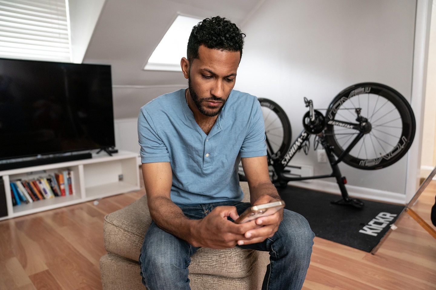 A man in his thirties who lives with MS reads an article on his cell phone.