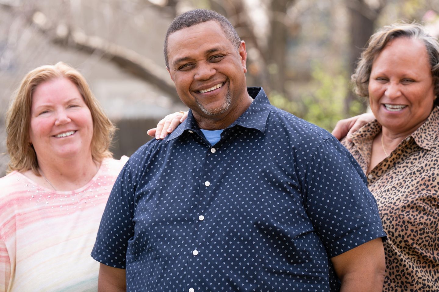 A man who lives with MS smiles while standing with his family.