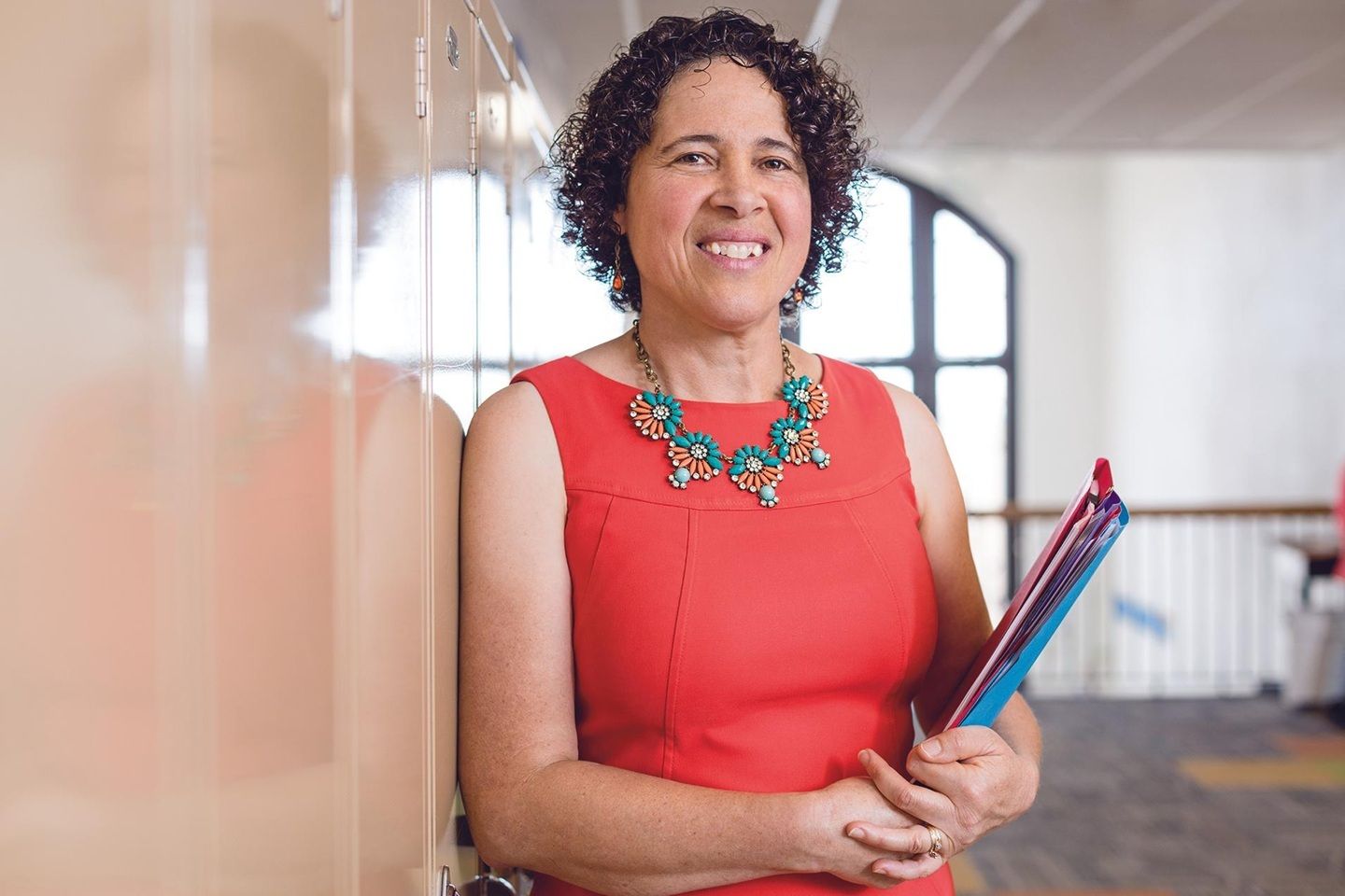 MS professional woman smiling while holding folders of paperwork.